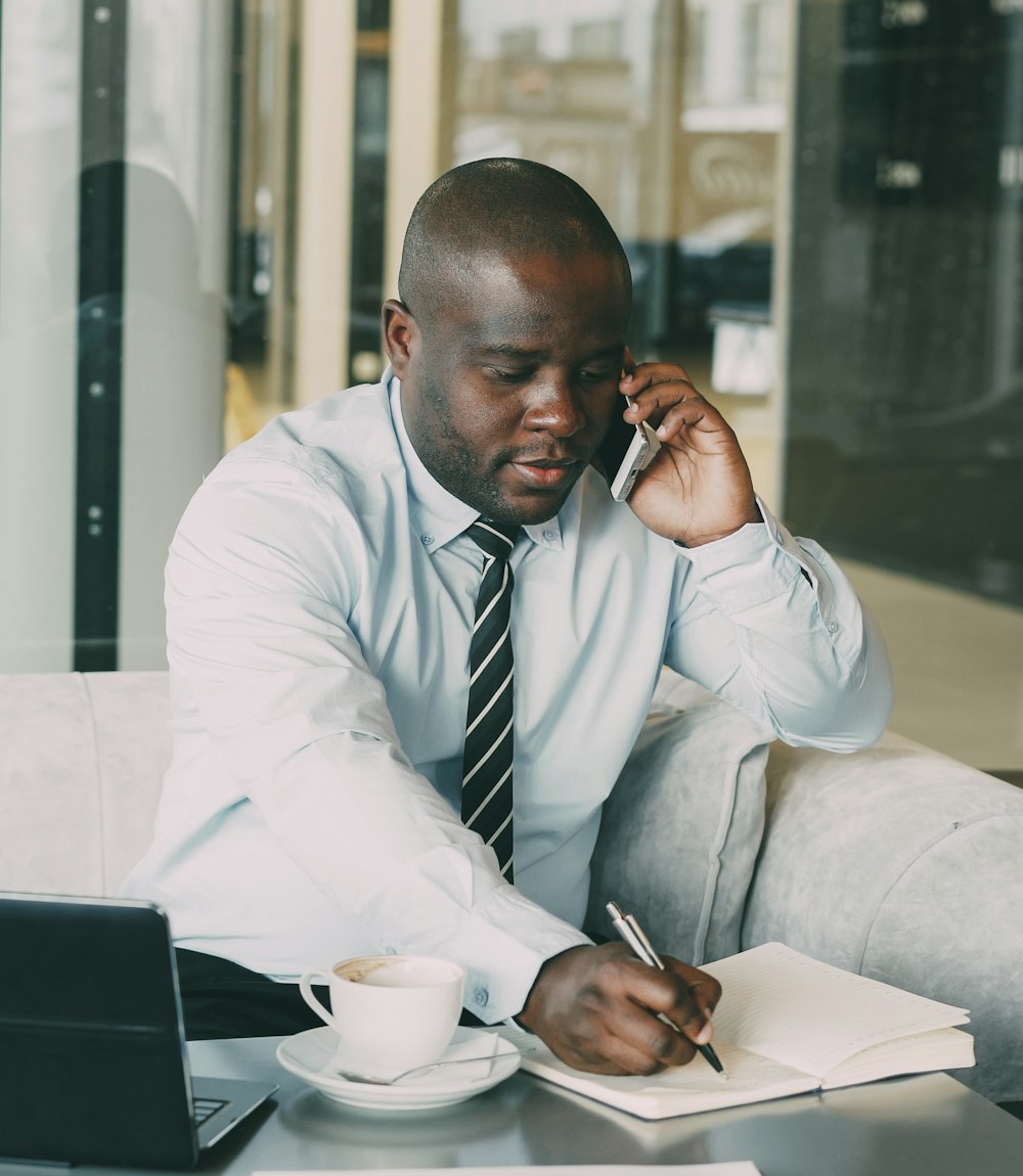Consultant on a call at his desk, taking notes for a client